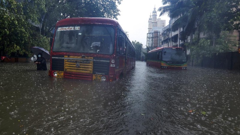 A motorist and a woman wade through a waterlogged street after heavy rains in Ahmedabad, India, Tuesday, May 18, 2021. Cyclone Tauktae, the most powerful storm to hit the region in more than two decades, packed sustained winds of up to 210 kilometers (130 miles) per hour when it came ashore in Gujarat state late Monday. (AP Photo/Ajit Solanki)