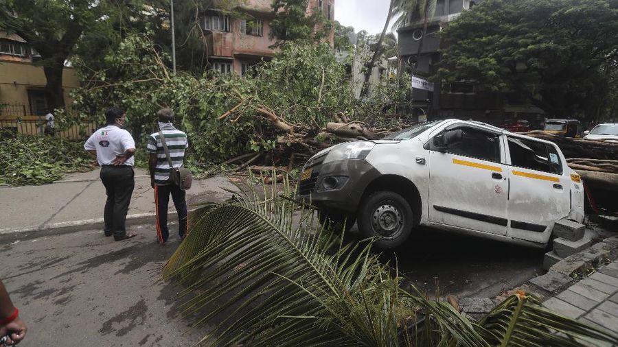 A motorist and a woman wade through a waterlogged street after heavy rains in Ahmedabad, India, Tuesday, May 18, 2021. Cyclone Tauktae, the most powerful storm to hit the region in more than two decades, packed sustained winds of up to 210 kilometers (130 miles) per hour when it came ashore in Gujarat state late Monday. (AP Photo/Ajit Solanki)