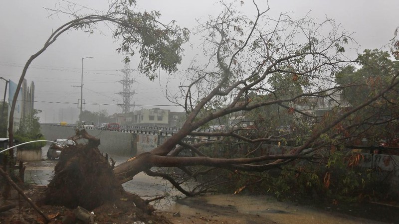 A motorist and a woman wade through a waterlogged street after heavy rains in Ahmedabad, India, Tuesday, May 18, 2021. Cyclone Tauktae, the most powerful storm to hit the region in more than two decades, packed sustained winds of up to 210 kilometers (130 miles) per hour when it came ashore in Gujarat state late Monday. (AP Photo/Ajit Solanki)