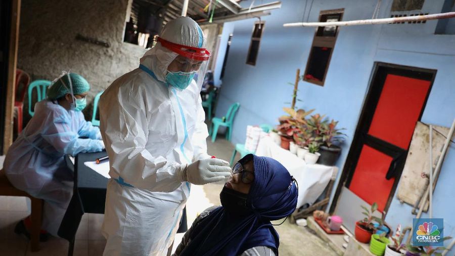 ‌Warga menjalani swab test PCR di kawasan RT 06/03 , Ciracas, Jakarta Timur, Kamis (20/Mei/2021). Sebanyak 24 warga atau delapan kepala keluarga (KK) di RT 06, RW 03, Kelurahan Ciracas, Jakarta Timur, terpapar Covid-19. Kawasan RT 03 langsung menerapkan lockdown atau Pengawasan Ketat Berskala Lokal (PKBL) di wilayah tersebut guna mencegah penyebaran Covid-19. Selama lockdown warga diwajibkan melaksanakan protokol kesehatan Covid-19 secara ketat dan dilarang keluar rumah apabila tidak ada keperluan mendesak. Pihaknya juga mengadakan swab test PCR massal warga setempat. Pihak kecamatan juga berkoordinasi dengan Dinas Sosial DKI Jakarta untuk memenuhi kebutuhan logistik warga RT tersebut. Delapan KK yang terpapar Covid-19 sebagian besar menjalani isolasi mandiri di Rumah Sakit Darurat Covid-19 Wisma Atlet Kemayoran. Pantauan CNBC Indonesia sejumlah warga terpaksa beraktifitas dari rumah. Okie yang keseharian nya menjadi badut di sekitar Ciracas terpaksa harus menahan diri dari rumah karena ada himbauan untuk tetap dirumah. 