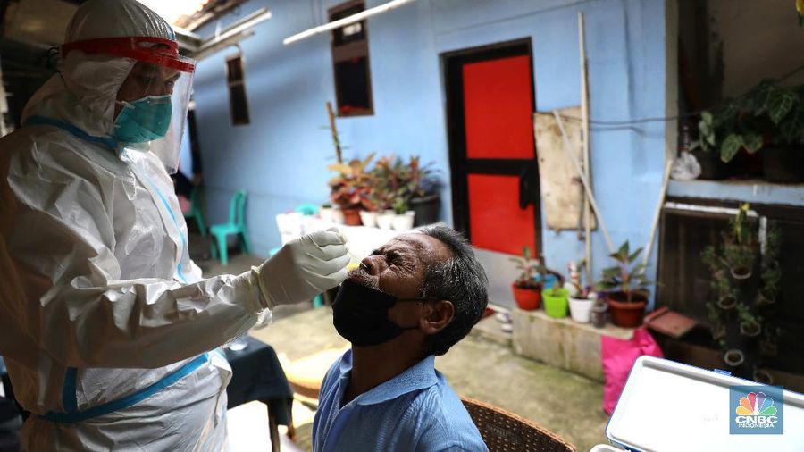 ‌Warga menjalani swab test PCR di kawasan RT 06/03 , Ciracas, Jakarta Timur, Kamis (20/Mei/2021). Sebanyak 24 warga atau delapan kepala keluarga (KK) di RT 06, RW 03, Kelurahan Ciracas, Jakarta Timur, terpapar Covid-19. Kawasan RT 03 langsung menerapkan lockdown atau Pengawasan Ketat Berskala Lokal (PKBL) di wilayah tersebut guna mencegah penyebaran Covid-19. Selama lockdown warga diwajibkan melaksanakan protokol kesehatan Covid-19 secara ketat dan dilarang keluar rumah apabila tidak ada keperluan mendesak. Pihaknya juga mengadakan swab test PCR massal warga setempat. Pihak kecamatan juga berkoordinasi dengan Dinas Sosial DKI Jakarta untuk memenuhi kebutuhan logistik warga RT tersebut. Delapan KK yang terpapar Covid-19 sebagian besar menjalani isolasi mandiri di Rumah Sakit Darurat Covid-19 Wisma Atlet Kemayoran. Pantauan CNBC Indonesia sejumlah warga terpaksa beraktifitas dari rumah. Okie yang keseharian nya menjadi badut di sekitar Ciracas terpaksa harus menahan diri dari rumah karena ada himbauan untuk tetap dirumah. 