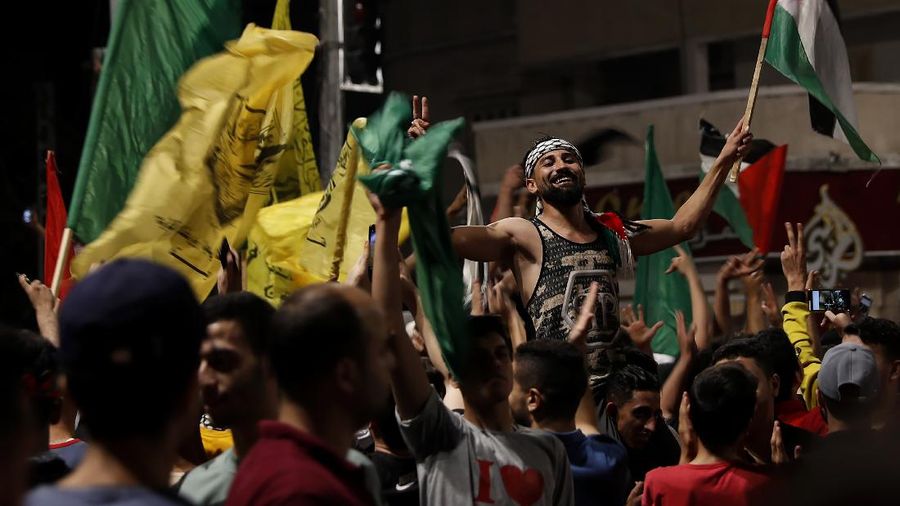 Palestinians chant slogans as they wave green Hamas and their national flags while celebrating the cease-fire agreement between Israel and Hamas in Gaza City, early Friday, May 21, 2021. (AP Photo/Adel Hana)