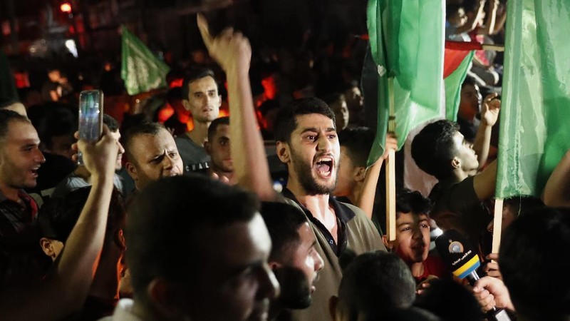 Palestinians chant slogans as they wave green Hamas and their national flags while celebrating the cease-fire agreement between Israel and Hamas in Gaza City, early Friday, May 21, 2021. (AP Photo/Adel Hana)