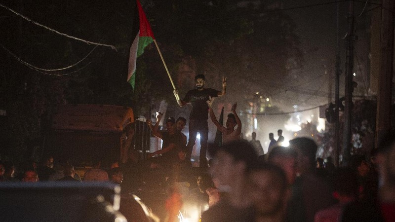 Palestinians chant slogans as they wave green Hamas and their national flags while celebrating the cease-fire agreement between Israel and Hamas in Gaza City, early Friday, May 21, 2021. (AP Photo/Adel Hana)