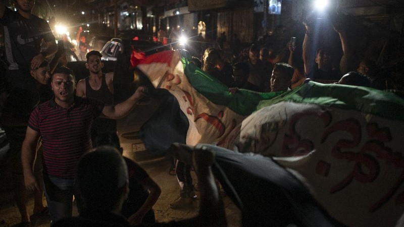 Palestinians chant slogans as they wave green Hamas and their national flags while celebrating the cease-fire agreement between Israel and Hamas in Gaza City, early Friday, May 21, 2021. (AP Photo/Adel Hana)