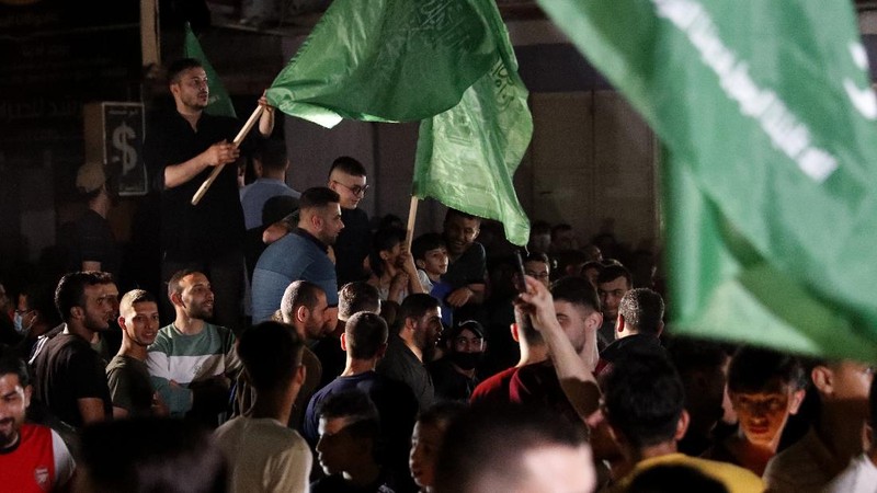 Palestinians chant slogans as they wave green Hamas and their national flags while celebrating the cease-fire agreement between Israel and Hamas in Gaza City, early Friday, May 21, 2021. (AP Photo/Adel Hana)