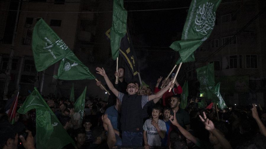 Palestinians chant slogans as they wave green Hamas and their national flags while celebrating the cease-fire agreement between Israel and Hamas in Gaza City, early Friday, May 21, 2021. (AP Photo/Adel Hana)