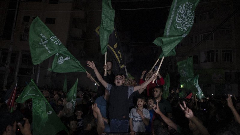 Palestinians chant slogans as they wave green Hamas and their national flags while celebrating the cease-fire agreement between Israel and Hamas in Gaza City, early Friday, May 21, 2021. (AP Photo/Adel Hana)