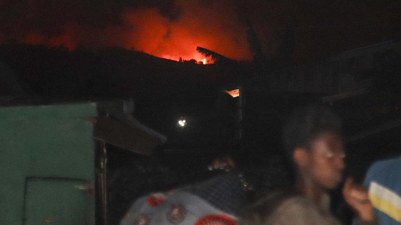 Two people are seen silhouetted against a night sky turned red by the eruption of Mount Nyiragongo, in Goma, Congo Saturday, May 22, 2021. Congo's Mount Nyiragongo erupted for the first time in nearly two decades Saturday, turning the night sky a fiery red and sending lava onto a major highway as panicked residents tried to flee Goma, a city of nearly 2 million. (AP Photo/Justin Kabumba)