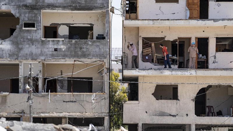 People walk by the rubble of the al-Jalaa building following a cease-fire reached after an 11-day war between Gaza's Hamas rulers and Israel, in Gaza City, Friday, May 21, 2021. The building housed The Associated Press bureau in Gaza City for 15 years. (AP Photo/John Minchillo)