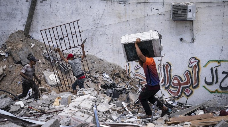 People walk by the rubble of the al-Jalaa building following a cease-fire reached after an 11-day war between Gaza's Hamas rulers and Israel, in Gaza City, Friday, May 21, 2021. The building housed The Associated Press bureau in Gaza City for 15 years. (AP Photo/John Minchillo)