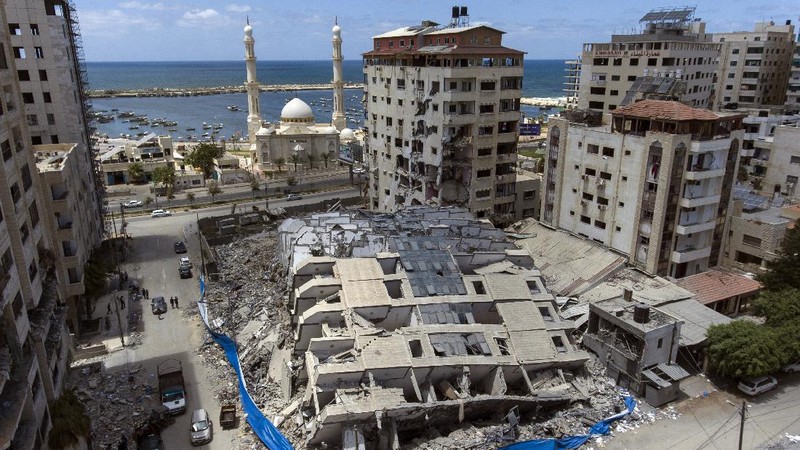 People walk by the rubble of the al-Jalaa building following a cease-fire reached after an 11-day war between Gaza's Hamas rulers and Israel, in Gaza City, Friday, May 21, 2021. The building housed The Associated Press bureau in Gaza City for 15 years. (AP Photo/John Minchillo)