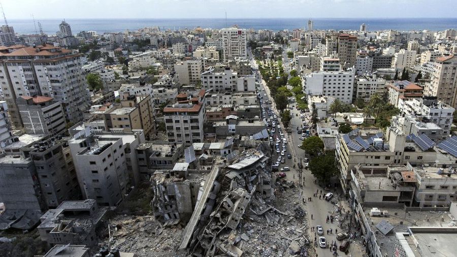 People walk by the rubble of the al-Jalaa building following a cease-fire reached after an 11-day war between Gaza's Hamas rulers and Israel, in Gaza City, Friday, May 21, 2021. The building housed The Associated Press bureau in Gaza City for 15 years. (AP Photo/John Minchillo)