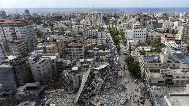 People walk by the rubble of the al-Jalaa building following a cease-fire reached after an 11-day war between Gaza's Hamas rulers and Israel, in Gaza City, Friday, May 21, 2021. The building housed The Associated Press bureau in Gaza City for 15 years. (AP Photo/John Minchillo)