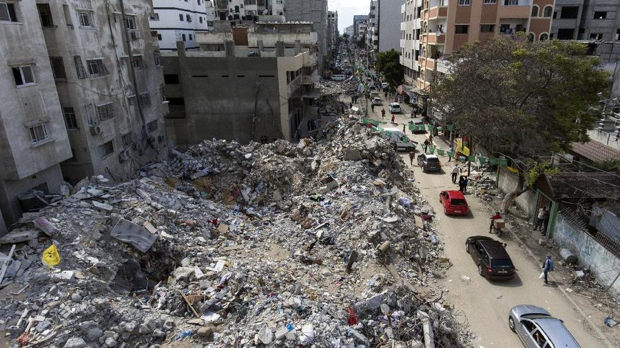 People walk by the rubble of the al-Jalaa building following a cease-fire reached after an 11-day war between Gaza's Hamas rulers and Israel, in Gaza City, Friday, May 21, 2021. The building housed The Associated Press bureau in Gaza City for 15 years. (AP Photo/John Minchillo)