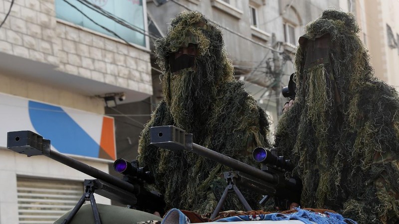 Masked militants from the Izzedine al-Qassam Brigades, a military wing of Hamas, march with their rifles a long the streets of Nusseirat refugee camp, central Gaza Strip, Friday, May 28, 2021. Arabic on the headband reads 