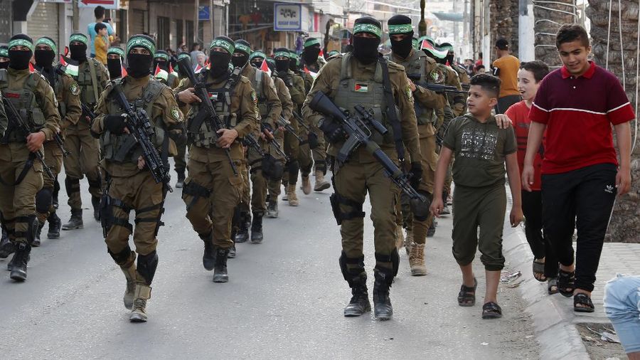 Masked militants from the Izzedine al-Qassam Brigades, a military wing of Hamas, march with their rifles a long the streets of Nusseirat refugee camp, central Gaza Strip, Friday, May 28, 2021. Arabic on the headband reads 