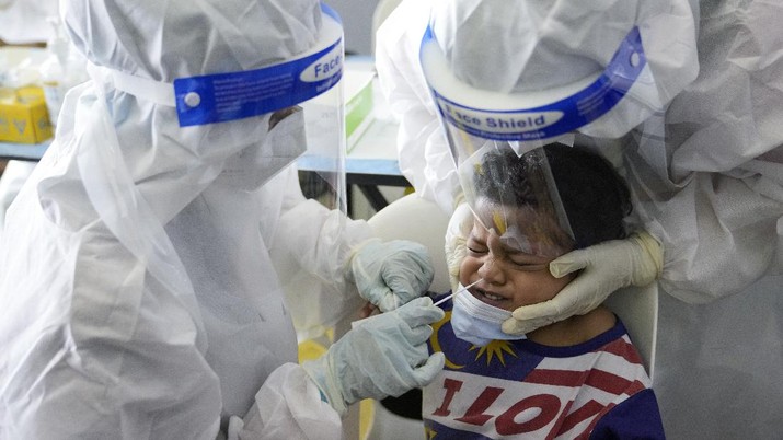 A medical worker collects swab sample from a boy during coronavirus testing at a COVID-19 testing center in Shah Alam, outskirts of Kuala Lumpur, Malaysia, Thursday, May 27, 2021. Malaysia's latest coronavirus surge has been taking a turn for the worse as surging numbers and deaths have caused alarm among health officials, while cemeteries in the capital are dealing with an increasing number of deaths. (AP Photo/Vincent Thian)