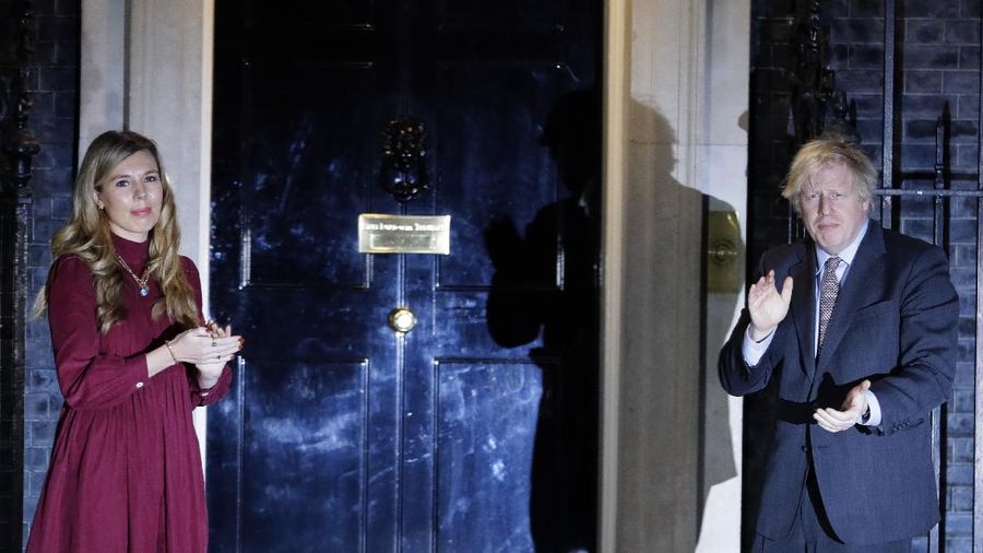 Britain's Prime Minister Boris Johnson and his partner Carrie Symonds, stand outside 10 Downing Street to join in the nationwide Clap for Carers to recognise and support National Health Service (NHS) workers and carers fighting the coronavirus pandemic, in London Thursday May 14, 2020. The highly contagious COVID-19 coronavirus has impacted on nations around the globe, many imposing self isolation and exercising social distancing when people move from their homes. (Victoria Jones / PA via AP)