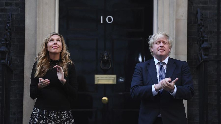 Britain's Prime Minister Boris Johnson and his partner Carrie Symonds, stand outside 10 Downing Street to join in the nationwide Clap for Carers to recognise and support National Health Service (NHS) workers and carers fighting the coronavirus pandemic, in London Thursday May 14, 2020. The highly contagious COVID-19 coronavirus has impacted on nations around the globe, many imposing self isolation and exercising social distancing when people move from their homes. (Victoria Jones / PA via AP)
