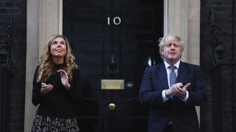 Britain's Prime Minister Boris Johnson and his partner Carrie Symonds, stand outside 10 Downing Street to join in the nationwide Clap for Carers to recognise and support National Health Service (NHS) workers and carers fighting the coronavirus pandemic, in London Thursday May 14, 2020. The highly contagious COVID-19 coronavirus has impacted on nations around the globe, many imposing self isolation and exercising social distancing when people move from their homes. (Victoria Jones / PA via AP)