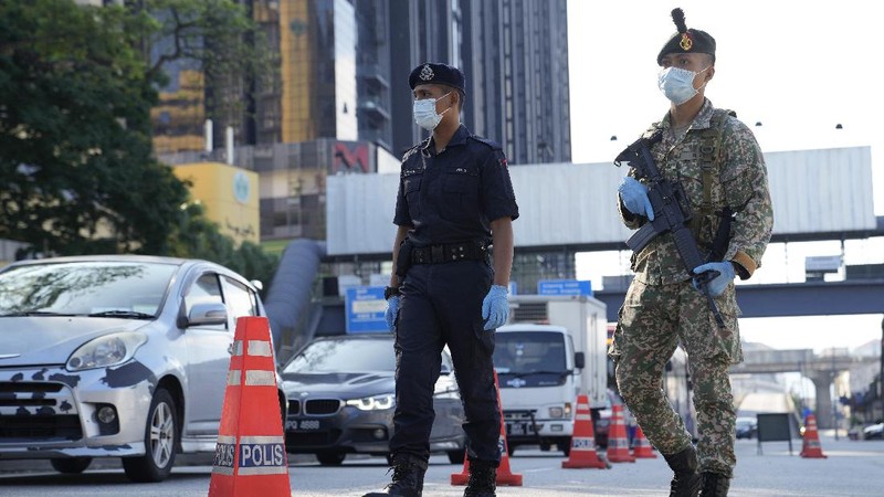 A man wearing a face mask walks along an empty road in front of the Twin Towers during the first day of Full Movement Control Order (MCO) in Kuala Lumpur, Malaysia, Tuesday, June 1, 2021. Malls and most businesses in Malaysia shuttered Tuesday as the country began its second near total coronavirus lockdown to tackle a worsening pandemic that has put its healthcare system on the verge of collapse. (AP Photo/Vincent Thian)