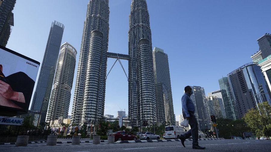 A man wearing a face mask walks along an empty road in front of the Twin Towers during the first day of Full Movement Control Order (MCO) in Kuala Lumpur, Malaysia, Tuesday, June 1, 2021. Malls and most businesses in Malaysia shuttered Tuesday as the country began its second near total coronavirus lockdown to tackle a worsening pandemic that has put its healthcare system on the verge of collapse. (AP Photo/Vincent Thian)