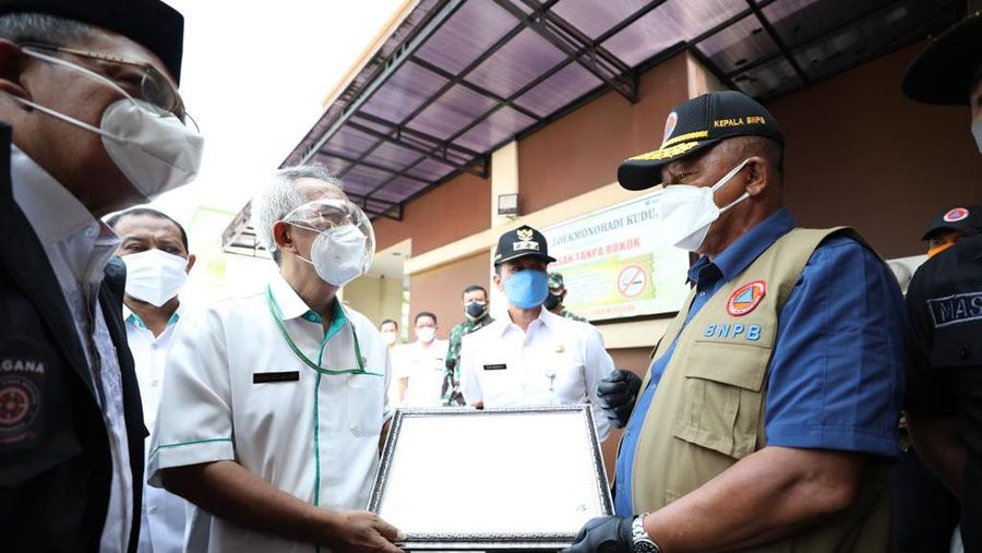 Kepala BNPB sekaligus Ketua Satgas Penanganan COVID-19 Ganip Warsito (kanan) menyerahkan bantuan secara simbolis kepada Pemerintah Kabupaten Kudus usai meninjau RSUD Lukmonohadi, Kudus, Jawa Tengah, Kamis (3/6).