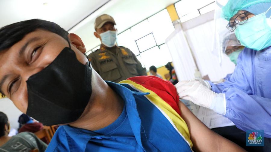 Tenaga kesehatan menyuntikan vaksin kepada warga di MTs As-Syafiiyah, Cilangkap, Jakarta, Kamis (3/6/2021). Vaksinasi massal di zona merah RT 03/ RW 03 Cilangkap akibat klaster halal bi halal itu dilakukan terhadap warga yang telah menjalani tes usap dengan hasil negatif. Vaksinasi diberikan kepada warga yang sebelumnya telah dinyatakan negatif Covid-19 hasil swab PCR. (CNBC Indonesia/Andrean Kristianto)