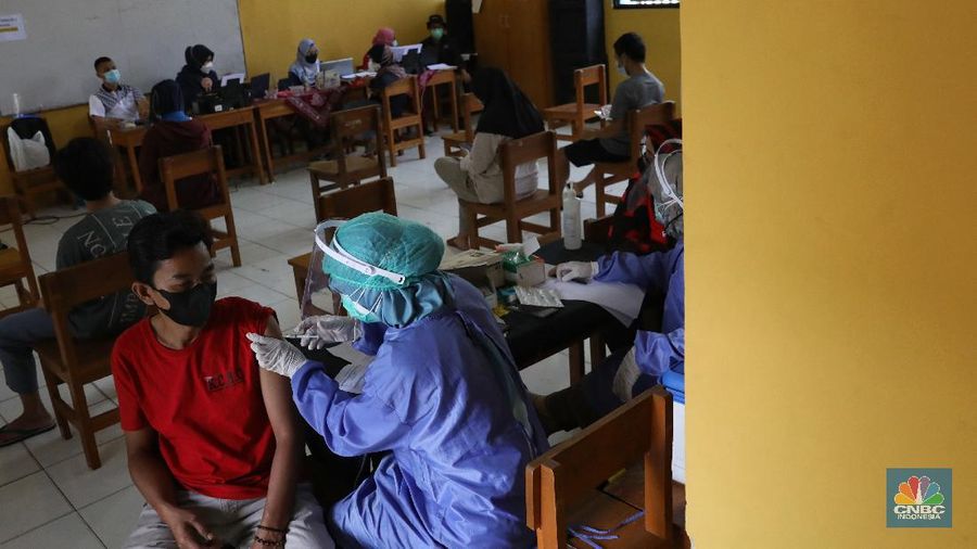 Tenaga kesehatan menyuntikan vaksin kepada warga di MTs As-Syafiiyah, Cilangkap, Jakarta, Kamis (3/6/2021). Vaksinasi massal di zona merah RT 03/ RW 03 Cilangkap akibat klaster halal bi halal itu dilakukan terhadap warga yang telah menjalani tes usap dengan hasil negatif. Vaksinasi diberikan kepada warga yang sebelumnya telah dinyatakan negatif Covid-19 hasil swab PCR. (CNBC Indonesia/Andrean Kristianto)