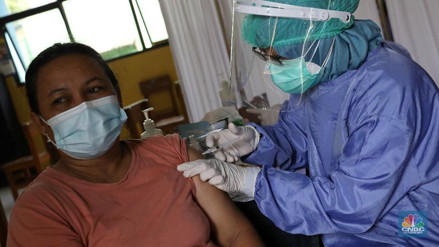 Tenaga kesehatan menyuntikan vaksin kepada warga di MTs As-Syafiiyah, Cilangkap, Jakarta, Kamis (3/6/2021). Vaksinasi massal di zona merah RT 03/ RW 03 Cilangkap akibat klaster halal bi halal itu dilakukan terhadap warga yang telah menjalani tes usap dengan hasil negatif. Vaksinasi diberikan kepada warga yang sebelumnya telah dinyatakan negatif Covid-19 hasil swab PCR. (վ/Andrean Kristianto)