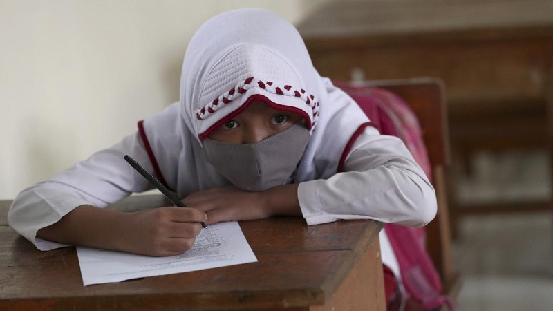 A student wearing a face mask sits spaced apart during a trial run of a class with COVID-19 protocols at an elementary school in Jakarta, Indonesia, Friday, June 4, 2021. The world's fourth-most populous country, with about 275 million people, has reported more coronavirus cases than any other Southeast Asian country. (AP Photo/Tatan Syuflana)