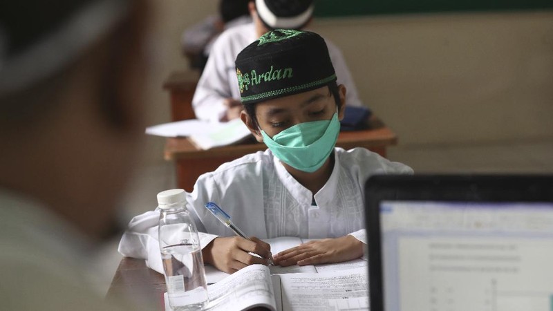 A student wearing a face mask sits spaced apart during a trial run of a class with COVID-19 protocols at an elementary school in Jakarta, Indonesia, Friday, June 4, 2021. The world's fourth-most populous country, with about 275 million people, has reported more coronavirus cases than any other Southeast Asian country. (AP Photo/Tatan Syuflana)