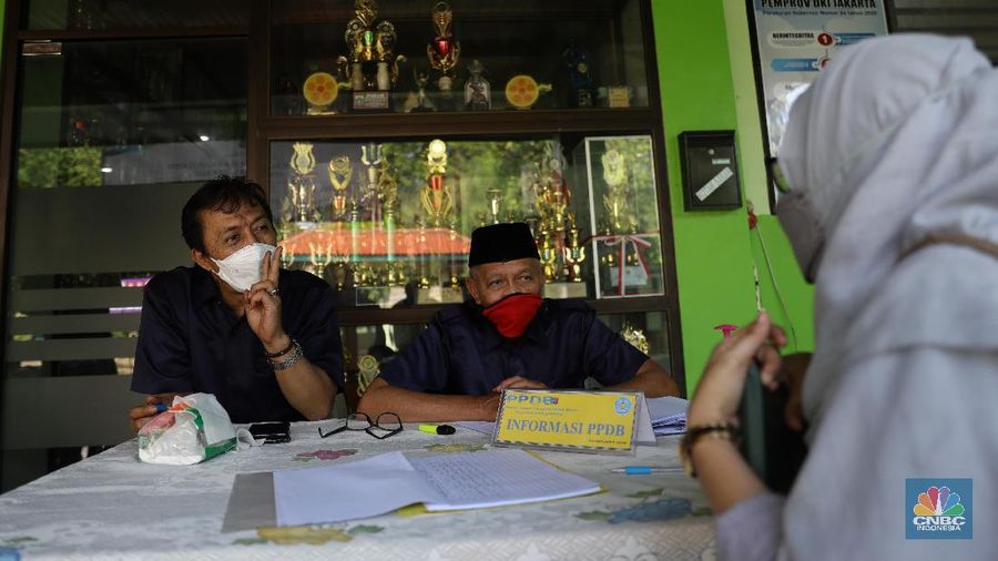 Orang tua murid mencari informasi pengajuan akun untuk mengikuti proses penerimaan Peserta Didik Baru (PPDB) Tahun Pelajaran 2021/2022 di Sekolah SMA Negeri 87 Jakarta, Senin (7/6). Proses penerimaan Peserta Didik Baru (PPDB) Tahun Pelajaran 2021/2022 di DKI Jakarta yang mulai dibuka sejak hari ini, Senin (7/6). Pada tahun ini, ada empat jalur pendaftaran yang dibuka meliputi jalur prestasi, afirmasi, zonasi, perpindahan tugas orang tua dan anak guru. Pada hari ini 7 Juni hingga 9 Juni 2021 PPDB dibuka khusus untuk jalur prestasi. Persyaratan PPDB Jakarta 2021 adalah ketentuan yang mewajibkan bahwa sekolah-sekolah negeri atau milik pemerintah yang ada di wilayah DKI Jakarta, hanya boleh menerima siswa yang terdaftar di Kartu Keluarga (KK) yang diterbitkan oleh Dinas Catatan Sipil dan Kependudukan Provinsi DKI Jakarta. Aturan ini PPDB DKI Jakarta 2021 juga telah diundangkan pada tanggal yang sama, dan dicatatkan dalam Berita Daerah Provinsi DKI Jakarta Tahun 2021 nomor 55005.
Pada pasal 1 ayat (11) Pergub No 32 Tahun 2021 tersebut meyebutkan, 