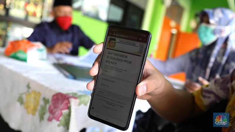 Orang tua murid mencari informasi pengajuan akun untuk mengikuti proses penerimaan Peserta Didik Baru (PPDB) Tahun Pelajaran 2021/2022 di Sekolah SMA Negeri 87 Jakarta, Senin (7/6). Proses penerimaan Peserta Didik Baru (PPDB) Tahun Pelajaran 2021/2022 di DKI Jakarta yang mulai dibuka sejak hari ini, Senin (7/6). Pada tahun ini, ada empat jalur pendaftaran yang dibuka meliputi jalur prestasi, afirmasi, zonasi, perpindahan tugas orang tua dan anak guru. Pada hari ini 7 Juni hingga 9 Juni 2021 PPDB dibuka khusus untuk jalur prestasi. Persyaratan PPDB Jakarta 2021 adalah ketentuan yang mewajibkan bahwa sekolah-sekolah negeri atau milik pemerintah yang ada di wilayah DKI Jakarta, hanya boleh menerima siswa yang terdaftar di Kartu Keluarga (KK) yang diterbitkan oleh Dinas Catatan Sipil dan Kependudukan Provinsi DKI Jakarta. Aturan ini PPDB DKI Jakarta 2021 juga telah diundangkan pada tanggal yang sama, dan dicatatkan dalam Berita Daerah Provinsi DKI Jakarta Tahun 2021 nomor 55005.
Pada pasal 1 ayat (11) Pergub No 32 Tahun 2021 tersebut meyebutkan, 