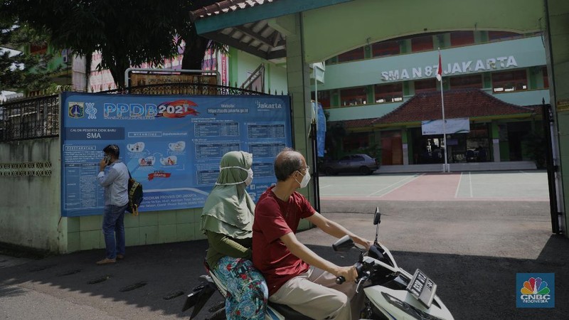 Orang tua murid mencari informasi pengajuan akun untuk mengikuti proses penerimaan Peserta Didik Baru (PPDB) Tahun Pelajaran 2021/2022 di Sekolah SMA Negeri 87 Jakarta, Senin (7/6). Proses penerimaan Peserta Didik Baru (PPDB) Tahun Pelajaran 2021/2022 di DKI Jakarta yang mulai dibuka sejak hari ini, Senin (7/6). Pada tahun ini, ada empat jalur pendaftaran yang dibuka meliputi jalur prestasi, afirmasi, zonasi, perpindahan tugas orang tua dan anak guru. Pada hari ini 7 Juni hingga 9 Juni 2021 PPDB dibuka khusus untuk jalur prestasi. Persyaratan PPDB Jakarta 2021 adalah ketentuan yang mewajibkan bahwa sekolah-sekolah negeri atau milik pemerintah yang ada di wilayah DKI Jakarta, hanya boleh menerima siswa yang terdaftar di Kartu Keluarga (KK) yang diterbitkan oleh Dinas Catatan Sipil dan Kependudukan Provinsi DKI Jakarta. Aturan ini PPDB DKI Jakarta 2021 juga telah diundangkan pada tanggal yang sama, dan dicatatkan dalam Berita Daerah Provinsi DKI Jakarta Tahun 2021 nomor 55005.
Pada pasal 1 ayat (11) Pergub No 32 Tahun 2021 tersebut meyebutkan, 
