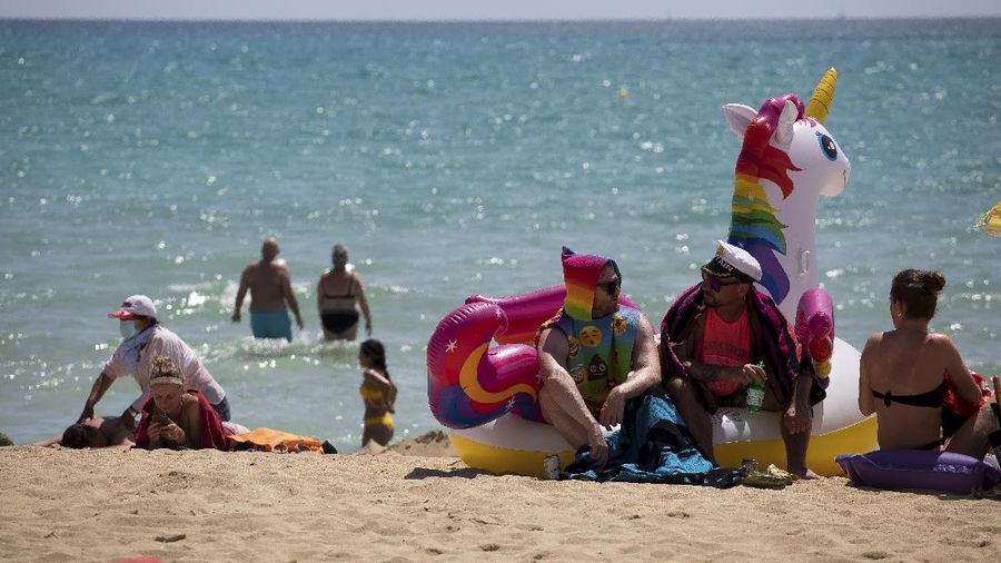 Tourists sunbathe on the beach at the Spanish Balearic Island of Mallorca, Spain, Monday, June 7, 2021. Spain is jumpstarting its summer tourism season by welcoming vaccinated visitors from most countries as well as European visitors who can prove they are not infected with coronavirus. It also reopened its ports to cruise ship stops on Monday. (AP Photo/Francisco Ubilla)