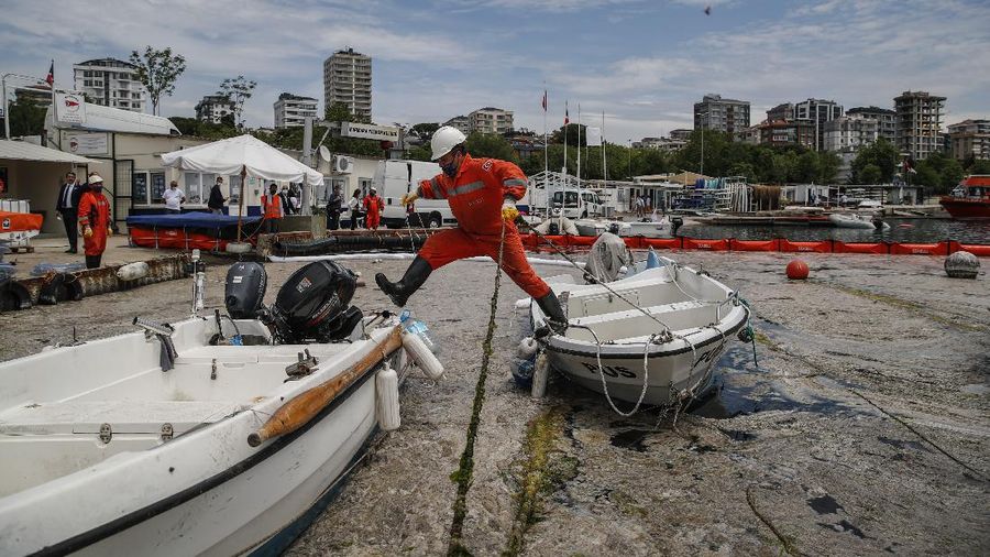 People ride a canoe by the Caddebostan shore, on the Asian side of Istanbul, Tuesday, June 8, 2021, surrounded by a huge mass of marine mucilage, a thick, slimy substance made up of compounds released by marine organisms, in Turkey's Marmara Sea. Turkey’s president has promised to rescue the Marmara Sea from an outbreak of “sea snot” that is alarming marine biologists and environmentalists. A huge mass of marine mucilage has bloomed in Turkey’s Marmara and the adjoining Black and Aegean Seas. Turkish President Recep Tayyip Erdogan said untreated waste dumped into the Marmara Sea and climate change had caused the bloom of the thick, slimy substance made up of compounds released by marine organisms, Istanbul, Turkey’s largest city, borders the sea. (AP Photo/Kemal Aslan)