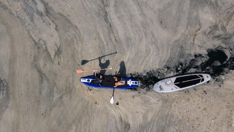 People ride a canoe by the Caddebostan shore, on the Asian side of Istanbul, Tuesday, June 8, 2021, surrounded by a huge mass of marine mucilage, a thick, slimy substance made up of compounds released by marine organisms, in Turkey's Marmara Sea. Turkey’s president has promised to rescue the Marmara Sea from an outbreak of “sea snot” that is alarming marine biologists and environmentalists. A huge mass of marine mucilage has bloomed in Turkey’s Marmara and the adjoining Black and Aegean Seas. Turkish President Recep Tayyip Erdogan said untreated waste dumped into the Marmara Sea and climate change had caused the bloom of the thick, slimy substance made up of compounds released by marine organisms, Istanbul, Turkey’s largest city, borders the sea. (AP Photo/Kemal Aslan)