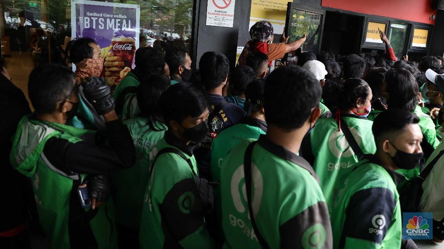 Puluhan ojol berkerumun untuk membeli promo BTS Meal di gerai McDonald's Mampang, Rabu (9/6/2021). Menu Mcdonald's yang berkolaborasi dengan BTS Meal dijual hari ini pukul 11.00 WIB. Pantauan վ di MC Donald Mampang sejumlah petugas Satpol PP Satgas Covid-19 di lokasi mencoba berbicara kepada manager MC Donald. Karena ramainya ojol Drive thru di mampang ditiadakan Ternyata di sejumlah Mcdonald's terlihat antrian para driver ojek online yang mendapatkan pesanan masyarakat untuk BTS Meal tersebut. Nama BTS Meal dan BTSxMcD menduduki peringkat satu dan kedua Trending Topik Twitter Indonesia. Masing-masing telah dipenuhi sebanyak 52.900 tweet dan 12.200 tweet. Selain itu ada juga yang mengabarkan jika aplikasi ojek online ditutup. Serta outlet McDonald's dikabarkan penuh untuk memesan BTS Meal. Salah satu driver ojol mengatakan pada վ bahwa ia sudah menunggu sejak pukul 11 hingga pukul 1.30 makanan belum juga bisa diambil. (վ/ Muhammad Sabki)