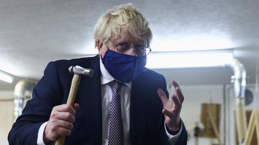 Britain's Prime Minister Boris Johnson holds a hammer after hammering a piece of Cornish tin into a model, as he visits the workshop of Scott Woyka, ahead of the G7 summit, in Falmouth, Cornwall, England, Thursday, June 10, 2021. (Tom Nicholson/Pool Photo via AP)