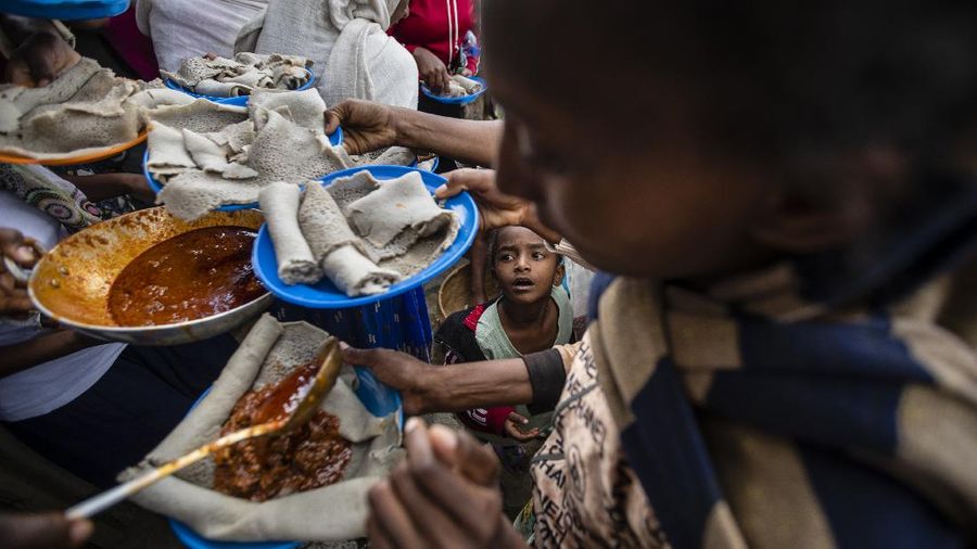 Ancaman Kelaparan Ethiopia A young boy looks up as displaced Tigrayans line up to receive food donated by local residents at a reception center for the internally displaced in Mekele, in the Tigray region of northern Ethiopia, on Sunday, May 9, 2021. The 15 kilograms of wheat, half a kilogram of peas and some cooking oil per person, to last a month — was earmarked only for the most vulnerable. That included pregnant mothers and elderly people. (AP Photo/Ben Curtis)