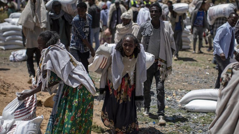 Elena, 7, center, lines up with other displaced Tigrayans to receive food donated by local residents at a reception center for the internally displaced in Mekele, in the Tigray region of northern Ethiopia, on Sunday, May 9, 2021. The 15 kilograms of wheat, half a kilogram of peas and some cooking oil per person, to last a month — was earmarked only for the most vulnerable. That included pregnant mothers and elderly people. (AP Photo/Ben Curtis)