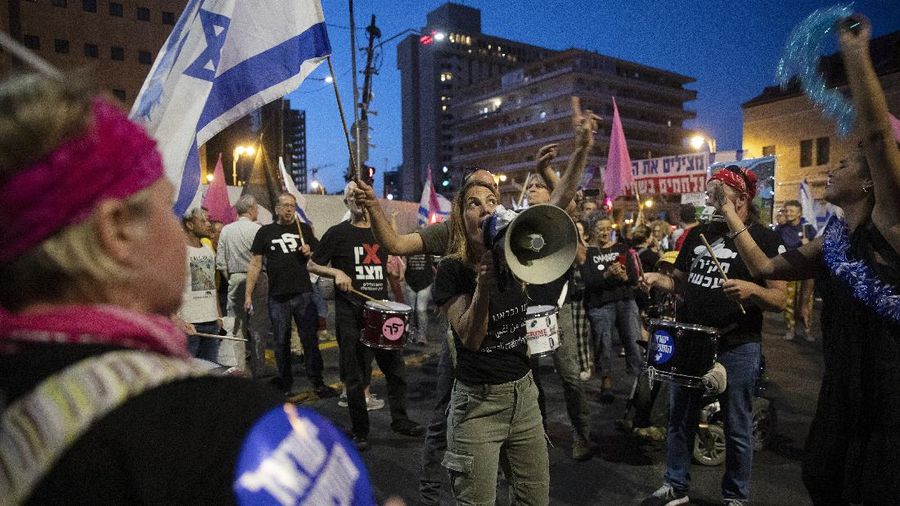 Israeli protesters march with a signs that reads 
