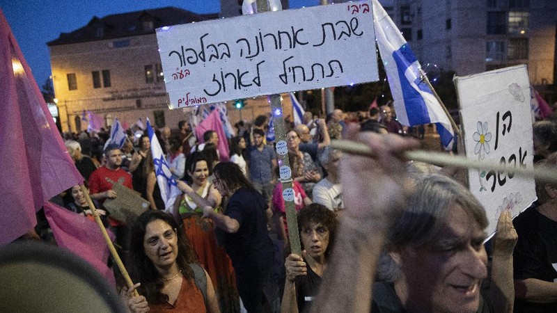 Israeli protesters march with a signs that reads 