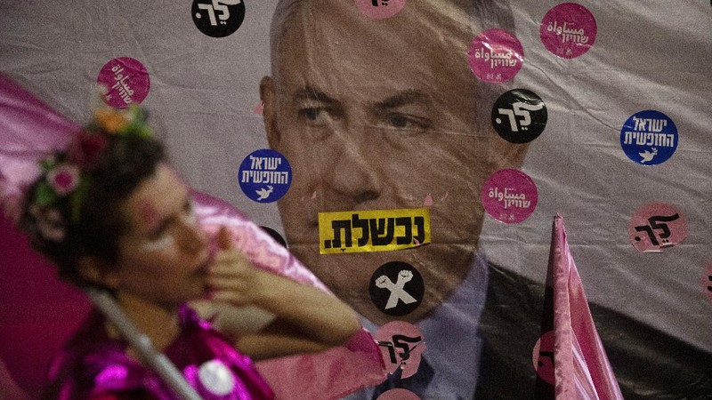 Israeli protesters march with a signs that reads 