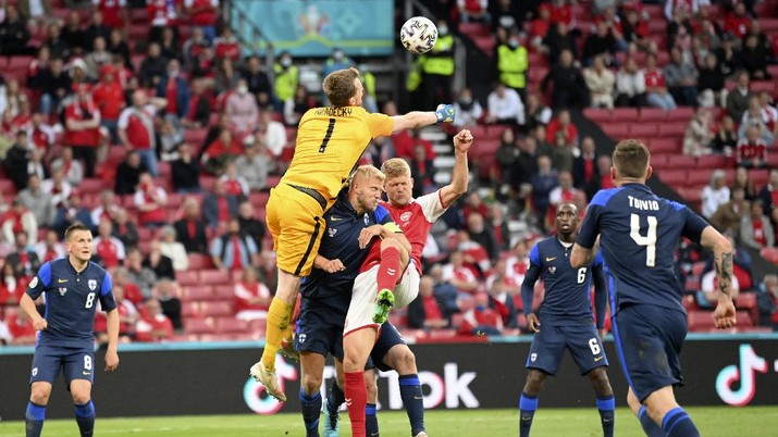 Finland's goalkeeper Lukas Hradecky punches the ball away from Denmark's Andreas Cornelius, center right, during the Euro 2020 soccer championship group B match between Denmark and Finland at Parken Stadium in Copenhagen, Saturday, June 12, 2021. (Stuart Franklin/Pool via AP)