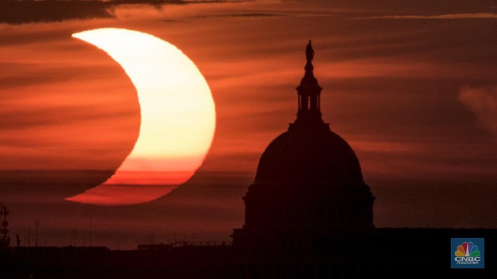 In this photo provided by NASA, a partial solar eclipse is seen as the sun rises to the left of the U.S. Capitol in Washington, Thursday, June 10, 2021, as seen from Arlington, Va. (Bill Ingalls/NASA via AP)
