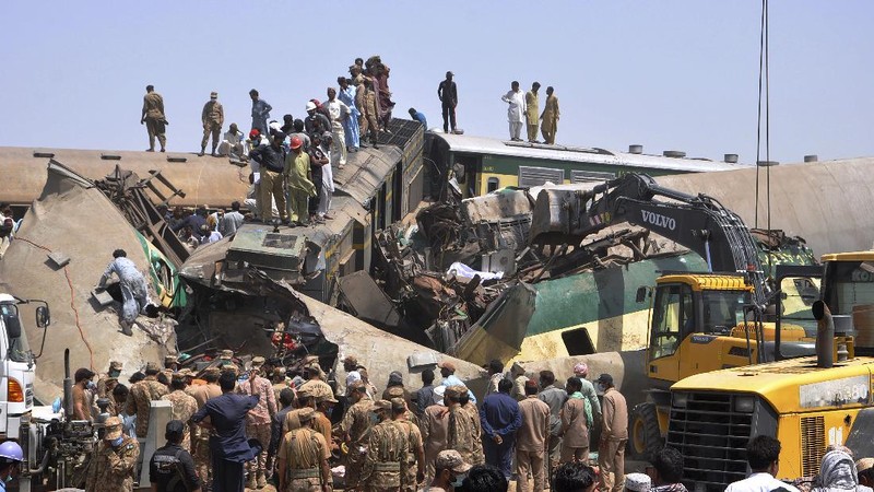 Soldiers and volunteers work at the site of a train collision in the Ghotki district of southern Pakistan, Monday, June 7, 2021. Two express trains collided early Monday, killing dozens of passengers authorities said, as rescuers and villagers worked to pull injured people and more bodies from the wreckage. (AP Photo/Waleed Saddique)