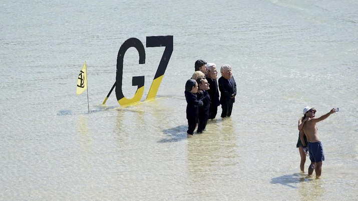 Para pengunjuk rasa mengenakan topeng yang menggambarkan para pemimpin G7 di pantai di Cornwall, Inggris. (AP/Jon Super) Para pengunjuk rasa mengenakan topeng yang menggambarkan para pemimpin G7 di pantai di Cornwall, Inggris. (AP/Jon Super)